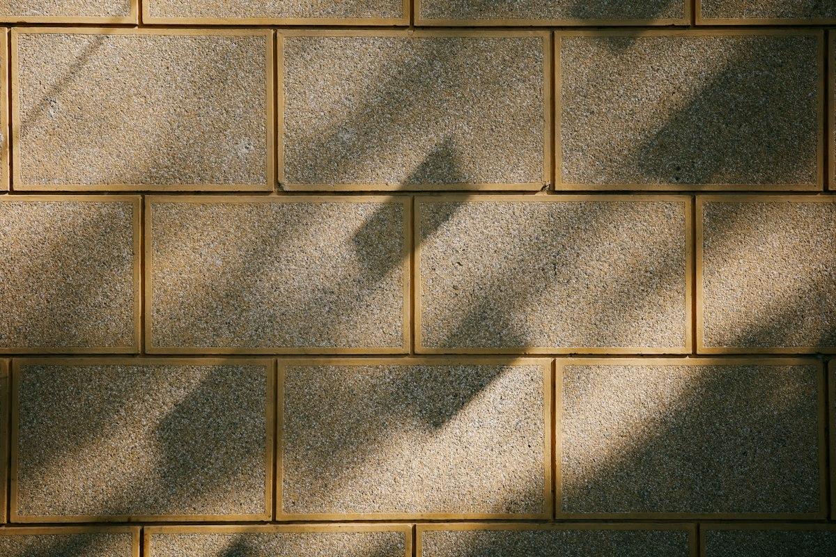 Dramatic diagonal shadow cutting across a paver surface