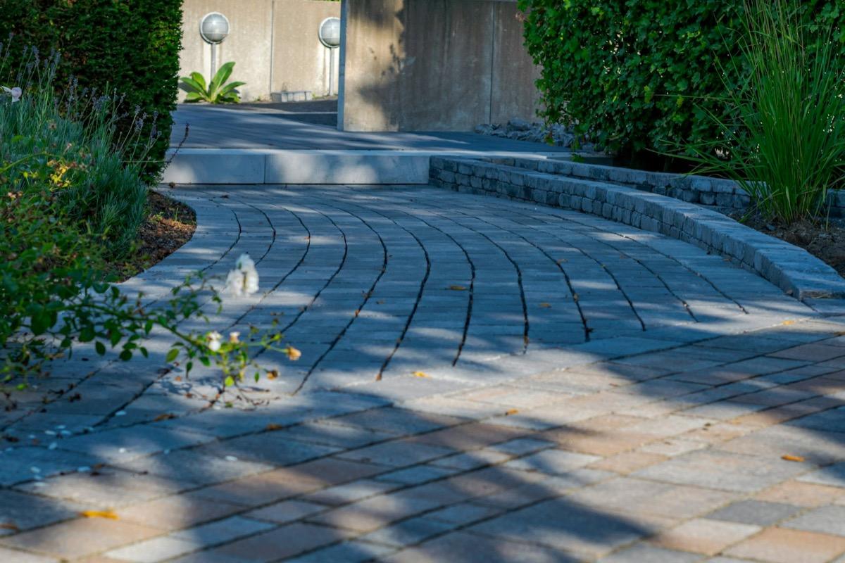 Curved paver driveway meeting a stacked-stone retaining edge